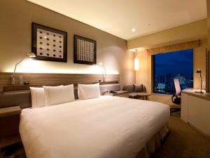 a bedroom with a large white bed and a window at The Royal Park Hotel Iconic Tokyo Shiodome in Tokyo