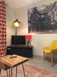 a living room with a tv and a yellow chair at Les Mermes à Veigy 10mn de Genève in Veigy-Foncenex