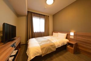 um quarto de hotel com uma cama e uma televisão em Dormy Inn Takamatsu Chuo Koenmae Natural Hot Spring em Takamatsu
