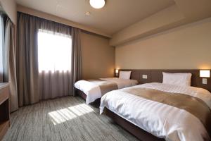 um quarto de hotel com duas camas e uma janela em Dormy Inn Takamatsu Chuo Koenmae Natural Hot Spring em Takamatsu