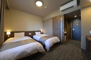 um quarto de hotel com duas camas e uma televisão em Dormy Inn Takamatsu Chuo Koenmae Natural Hot Spring em Takamatsu