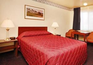 サンタクララにあるDriftwoodの赤いベッドとデスクが備わるホテルルームです。
