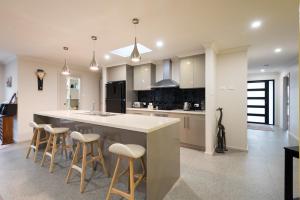 a kitchen with a large island with bar stools at Euphoria House in Wynyard