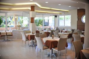 a dining room with tables and chairs and windows at Argiro Village in Afantou
