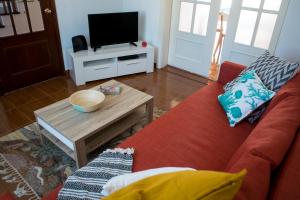 Una sala de estar con un sofá rojo y un televisor. en Populo Beach House, en São Roque