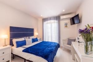 Un dormitorio con una cama azul y blanca y una ventana. en Suites @ Portarade, en Ferragudo