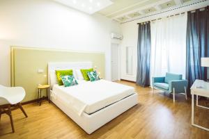 a bedroom with a white bed and a blue chair at Bluemoon Sardinia Roof Garden Jacuzzi in Cagliari