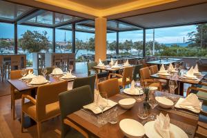 a restaurant with wooden tables and chairs and windows at Hotel Maritime in Krk