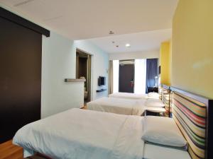 a hotel room with three beds and a tv at Y Loft in Hong Kong