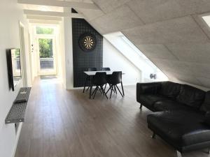 a living room with a couch and a table with chairs at Tollundgaard Golf Park & Apartments in Funder Kirkeby