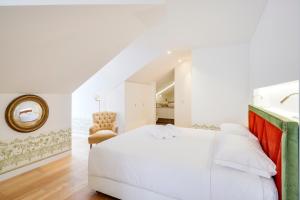um quarto com uma cama branca e uma cadeira em Residentas Aurea em Lisboa