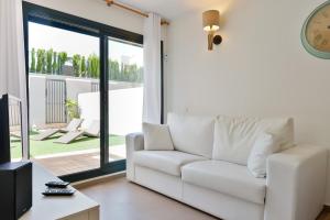 a living room with a white couch and a clock at Can Marcel in Cala Tarida