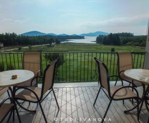 a balcony with tables and chairs and a view of a lake at Guesthouse Paralimnia in Kalyvia