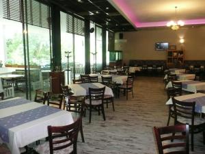 a dining room with tables and chairs and windows at Hotel Park in Burgas