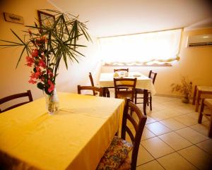 una mesa amarilla con un jarrón de flores. en B&B Casalotto Inn, en Aci SantʼAntonio