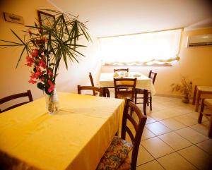 a yellow table with a vase of flowers on it at B&B Casalotto Inn in Aci SantʼAntonio