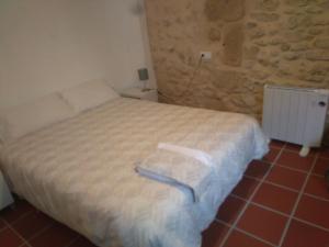 1 dormitorio con cama y pared de piedra en Casa Rural La Tia Rosa, en Chulilla