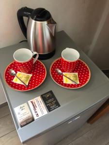 Affittacamere Ca' d' Giuanot في Miroglio: طاولة مع اثنين من الأطباق الحمراء وقدر الشاي