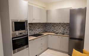 una cucina con armadi bianchi e frigorifero in acciaio inossidabile di Dream Houses a Lourdata