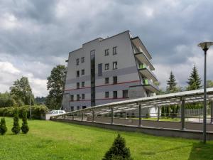 a building with a walkway in front of a green park at VisitZakopane - Cristal Apartment in Zakopane