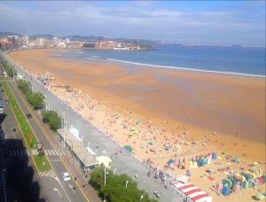 een strand vol met veel mensen met parasols bij ESCALERA 14 in Gijón