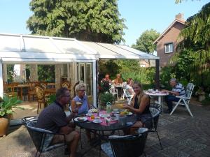 een groep mensen die aan een tafel op een patio zitten bij B&B De Kleine Wijngaard in Roggel