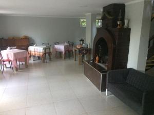 a living room with a fireplace and tables and chairs at guest house QEDI in Jvari