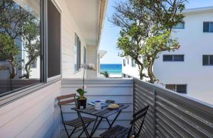 una pequeña mesa en un balcón con vistas al océano en Sandbox Apartments, en Gold Coast