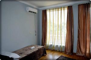 um quarto com uma cama e uma grande janela em guest house QEDI em Jvari