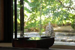 a table with two glasses in front of a window at Taketomijima Akaneya in Taketomi