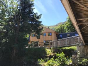 een houten huis met een brug en een boom bij Glen Nevis Youth Hostel in Fort William