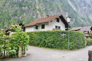 una casa con una siepe di fronte a un edificio di Alpen Apartement a Hallstatt