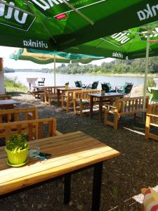 a row of wooden tables with green umbrellas at Apartment Kapetanovic in Bosanski Šamac