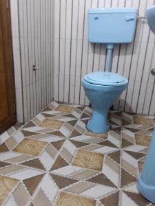 uma casa de banho com um WC azul num piso de azulejo em Vamoose Nilakanta em Sukhia Pokhari