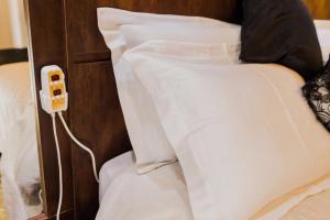 Una cama con almohadas blancas y un teléfono. en Pousada Cafe Poesia, en Campos do Jordão