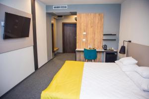 Hotel Bistrita في بيستريتسا: غرفة بسرير ومكتب وتلفزيون