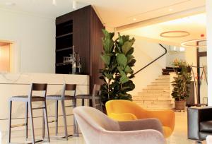 a living room with yellow chairs and a staircase at Hotel Federale in Lugano