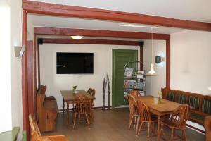 a dining room with two tables and a flat screen tv at Harresø Kro in Harresö Gaarde