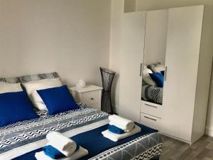 a bedroom with two beds with blue pillows and a mirror at Grand F3 Paris Stade de France & La Villette, 6 pers - Metro 7 in Aubervilliers +21 photos