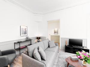 a living room with a couch and a tv at LivinParis - Luxury 4 Bedrooms Opera I in Paris