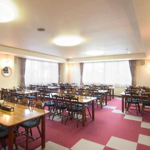 a dining room with tables and chairs and windows at Frontier Sunrise in Kami-furano