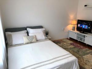 een slaapkamer met een wit bed en een televisie bij Apartment Ilija in Zadar