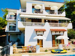 a building with tables and umbrellas next to a pool at Rooms Olympia in Gialiskari