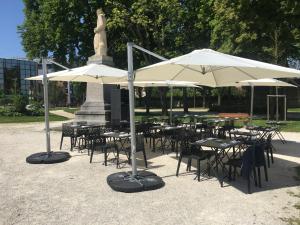 a group of tables and chairs with umbrellas in a park at Hôtel Restaurant Des Remparts in Chaumont