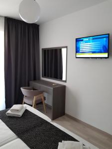 een slaapkamer met een bed, een bureau en een televisie bij Les Palmiers Petrou Apartments in Larnaka