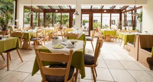 ein Restaurant mit Tischen, Stühlen und Fenstern in der Unterkunft Hotel Janssen in Bodenheim