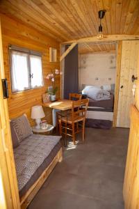 a room with a bed and a table in a cabin at La Maison du Bonheur Roulotte in Saint-Ouen-sous-Bailly