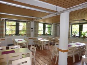 ein Restaurant mit Tischen, Stühlen und Fenstern in der Unterkunft Campus Prackenfels in Altdorf bei Nürnberg