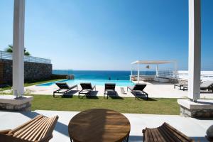 a patio with chairs and a table and the ocean at Elements Villas in Lartos +150 photos
