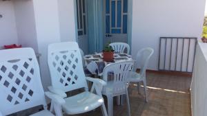 a table with white chairs and a potted plant on it at Quartos para Ferias in Fuzeta